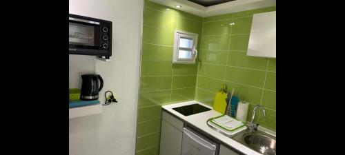 a green tiled kitchen with a sink and a microwave at Résidence des Iles in Les Abymes