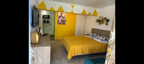 a bedroom with a bed and a yellow wall at Résidence des Iles in Les Abymes