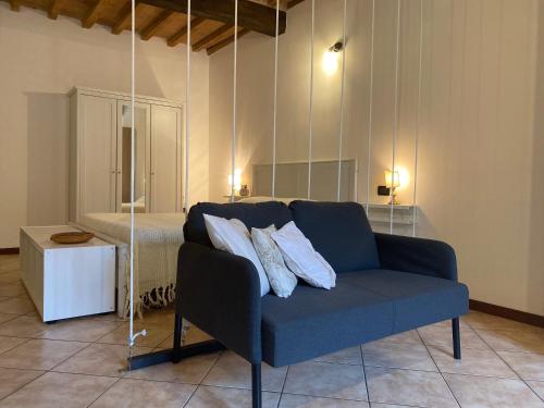 a living room with a blue couch and a bed at Teatro Inn - Timeless Charm in Correggio