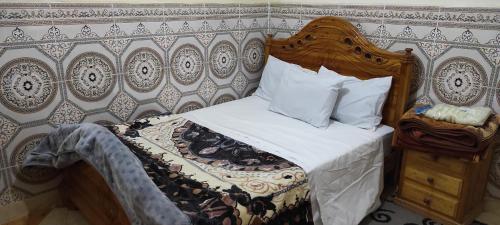 sypialnia z łóżkiem z drewnianym zagłówkiem w obiekcie aDAM w mieście Dakhla