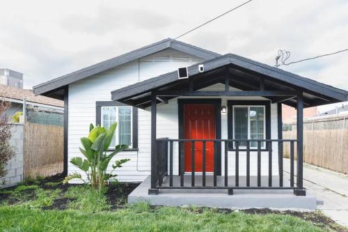 a small white house with a red door at A stunning 2bedroom 2bath private home near Sofi Stadium, Kia Forum, and Intuit Dome in Los Angeles