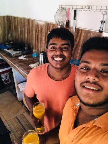 two men smiling while holding a glass of orange juice at Dolphin Village in Kalpitiya