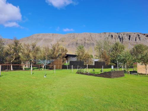 un parco con un campo con una montagna sullo sfondo di Nýlegur sumarbústaður/friðsæld a Mosfellsbær