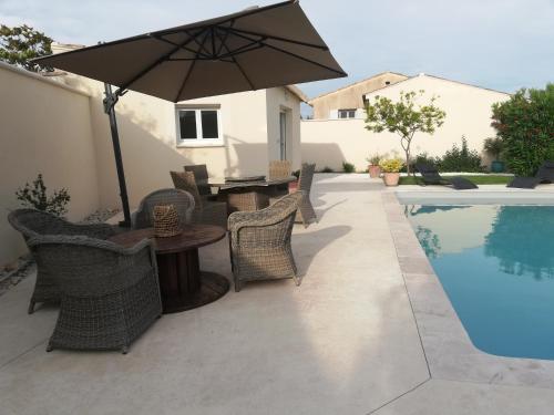 a patio with a table and umbrella next to a swimming pool at Studio NEUF avec piscine in Tulette