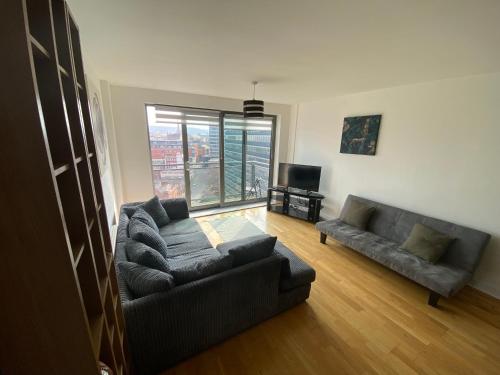 a living room with a couch and a television at EEJs Beautiful 2 bed Apartment - Sheffield centre in Sheffield