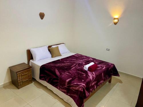 um quarto com uma cama com um edredão roxo em Charming Garden near Beach+bike em Dahab