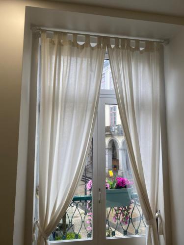 una ventana con cortinas blancas y un balcón con flores en Barão 35 Guest House en Braga