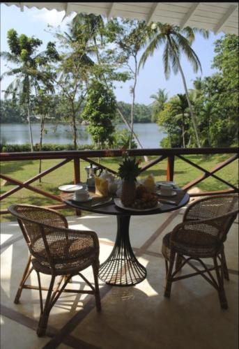 a table and chairs on a balcony with a view of the water at The Lake House Koggala in Galle