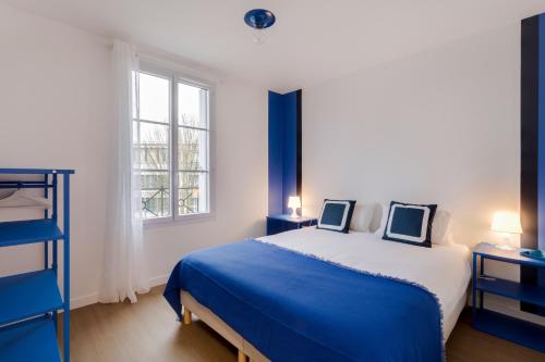 um quarto com uma cama azul e branca e uma janela em La Serrisienne 7 - Val d'Europe - Disneyland Paris - 6 à 8 Personnes em Serris