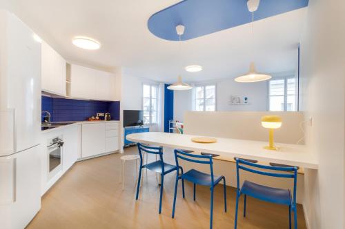 une cuisine avec une grande table blanche et des chaises bleues dans l'établissement La Serrisienne 7 - Val d'Europe - Disneyland Paris - 6 à 8 Personnes, à Serris