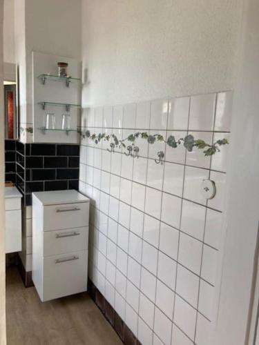 a bathroom with white tiled walls and a white cabinet at Wohnen im Grünen bei der Töpferei in Erfurt