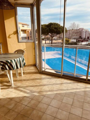 d'un balcon avec une table et une vue sur la piscine. dans l'établissement JARDINS DU CAP Joli T2 avec piscine Plage Richelieu Cap d'Agde, au Cap d'Agde