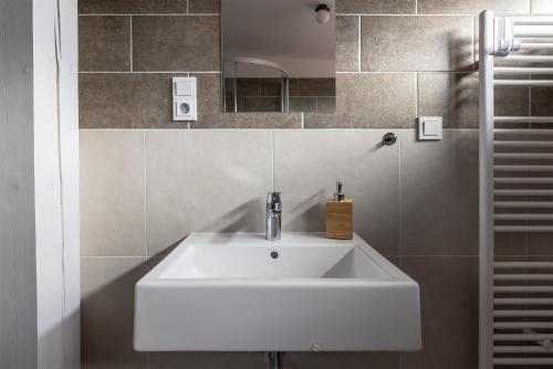 y baño con lavabo blanco y espejo. en Apartmány v lomnickém pivovaru, en Lomnice nad Popelkou