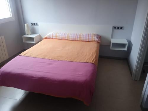 a small bedroom with a bed with purple and orange sheets at Sofia home in San Antonio de Benagéber