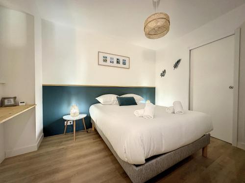 une chambre avec un grand lit blanc et une table dans l'établissement *L'Armorique* ravissant appartement cosy, à Brest