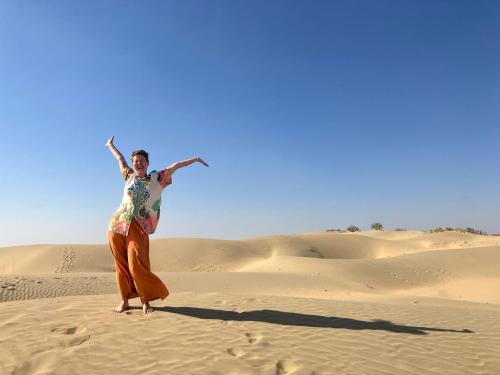 a woman standing in the sand in the desert at Marigold Home Stay in Jaisalmer