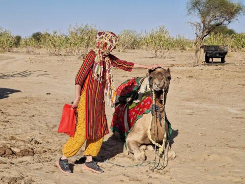 a woman standing next to a dog in the desert at Marigold Homestay in Jaisalmer