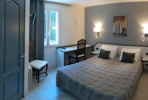 a bedroom with a bed and a desk and a chair at Hôtel Le Pradet in Vacqueyras