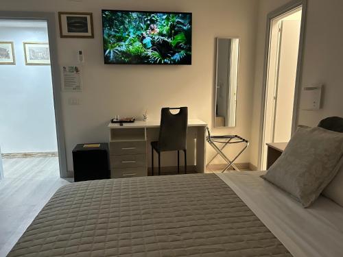 una camera da letto con un letto, una scrivania e una TV a parete di Dolce Dormire a Castiglione del Lago