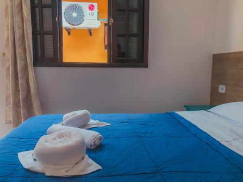 a bed with towels on it with a window at Pousada Acqua Bella PISCINA CLIMATIZADA in Bertioga