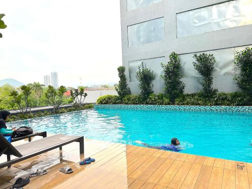 een persoon die zwemt in een zwembad naast een gebouw bij Neu Suites By Serenity Vacation Homes in Kuala Lumpur