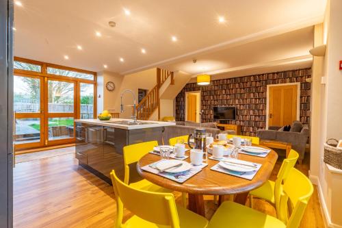 a kitchen and living room with a wooden table and yellow chairs at Bullrush Barn, Brecon Beacons walkers retreat in Brecon