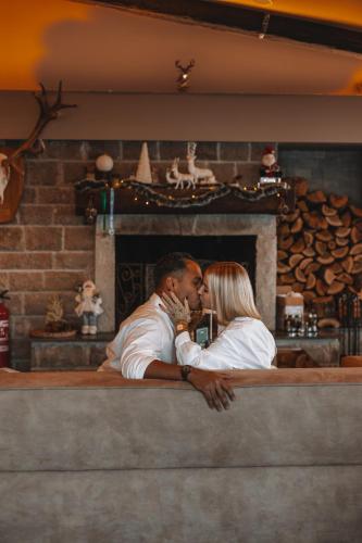 a man and a woman kissing in front of a fireplace at Hotel and SPA Moreni in Sofia