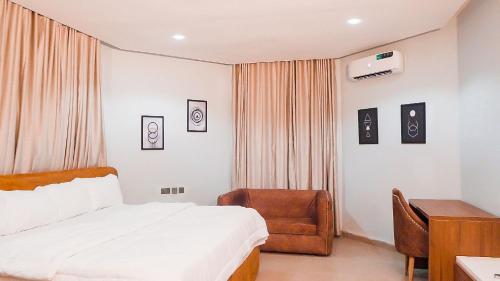 a bedroom with a bed and a chair and a desk at Cedarwood Apartments in Abuja