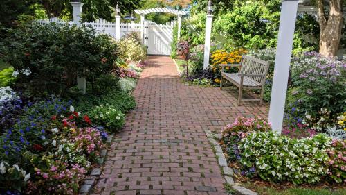 a brick path in a garden with a bench at Dan'l Webster Inn and Spa in Sandwich