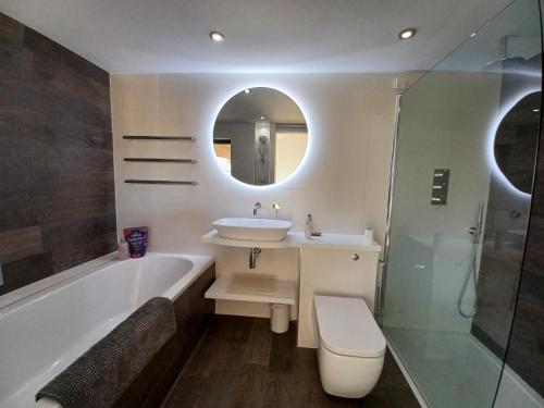 a bathroom with a sink and a tub and a mirror at Pound Orchard Bed and Breakfast in Petersfield