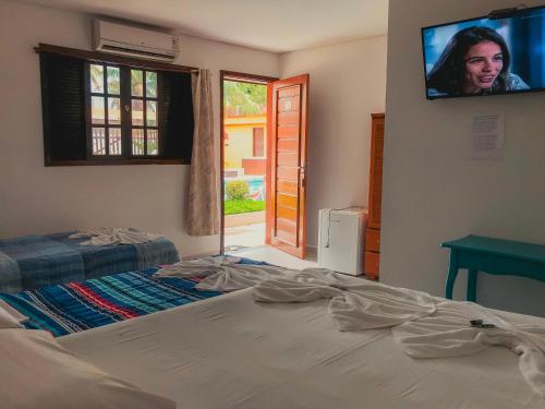 a bedroom with a bed and a tv on the wall at Pousada Acqua Bella PISCINA CLIMATIZADA in Bertioga