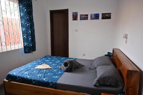 a bedroom with a bed with a blue comforter at Les Amazones Rouges Chambre Bleue in Ouidah