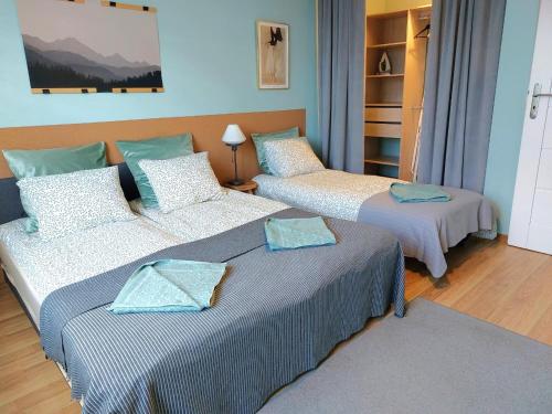 two beds in a room with blue walls at Apartamenty Nova na Krakowskiej No 3 in Bielsko-Biała