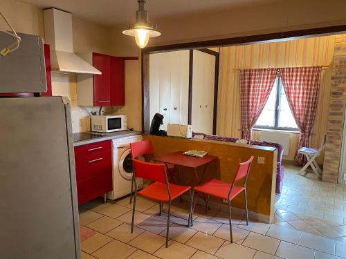 une cuisine avec des placards rouges, une table et des chaises dans l'établissement Locations de la centrale de Belleville, à Neuvy-sur-Loire