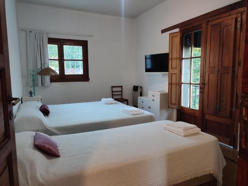 1 dormitorio con 2 camas, TV y ventanas en El depto de Bowie en Santa Rosa de Calamuchita