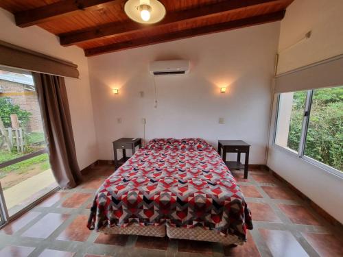 ein Schlafzimmer mit einem Bett in einem Zimmer mit Fenstern in der Unterkunft Rancho Aparte in Ituzaingó