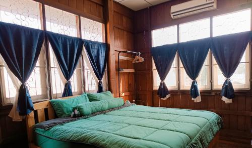 a bedroom with a bed with blue sheets and windows at PAI BAAN Homestay ปายบ้าน โฮมสเตย์ ถนนคนเดินปาย in Pai