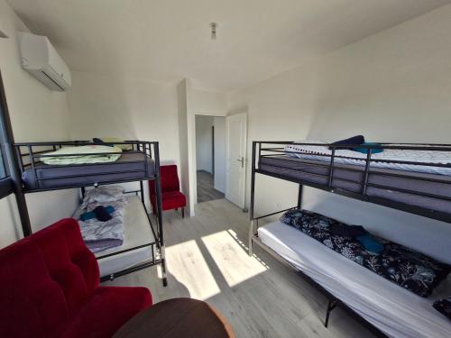 a room with three bunk beds and a red couch at La Villa Caennaise-Caen in Caen