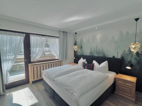 ein Schlafzimmer mit einem großen Bett und einem großen Fenster in der Unterkunft Schwarzwald-Hotel Kraeutle in Feldberg