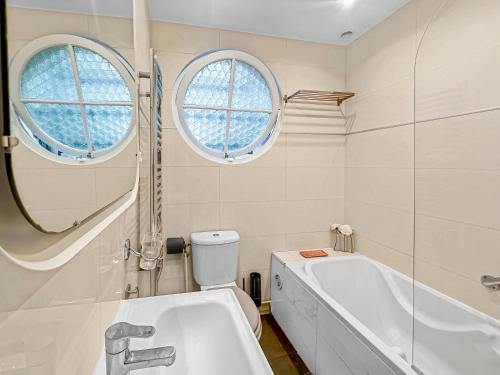 La salle de bains est pourvue d'une baignoire, de toilettes et de 2 fenêtres. dans l'établissement La Perle de Cannes, à Cannes