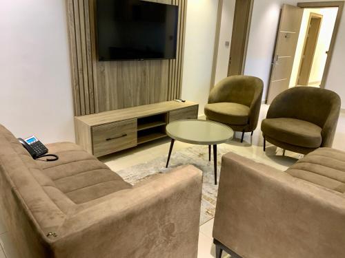 Polo Grand Hotel في Maiduguri: غرفة معيشة مع أريكة وكراسي وتلفزيون