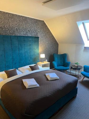 a bedroom with a large bed and blue chairs at Penzión Aira in Zvolen