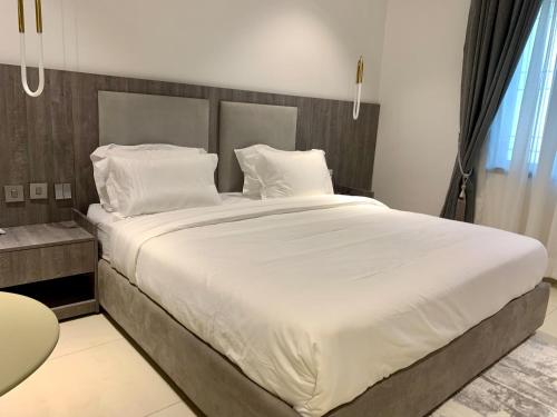 Polo Grand Hotel في Maiduguri: غرفة نوم بسرير كبير عليها شراشف ووسائد بيضاء