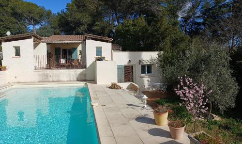 a villa with a swimming pool in front of a house at Charmant petit studio avec jardin et piscine in Nîmes