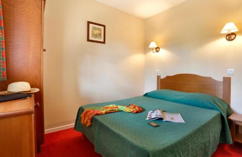 um quarto de hotel com uma cama com um livro em Appart 1 chb lit double dans jolie résidence du Lac em Monflanquin