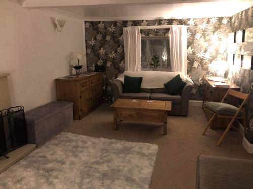 ein Wohnzimmer mit einem Sofa und einem Tisch in der Unterkunft Lochside Retreat, Stranraer - Cottage by the loch! in Stranraer
