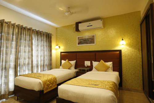 Devanhalli的住宿－微風套房酒店，酒店客房设有两张床和窗户。