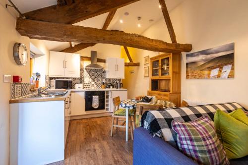 a kitchen and a living room with a blue couch at Dragonfly Cottage, Canal location in Brecon