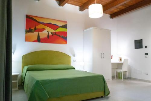 Un dormitorio con una cama verde y una pintura en la pared en Stellaris en Siderno Marina