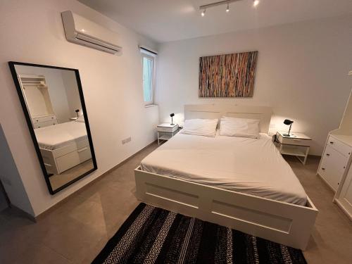 The Willows apartment nr. 3 في Is-Swieqi: غرفة نوم بيضاء مع سرير ومرآة